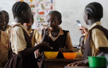 young children in group smiling at one another and eating food