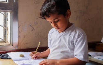 young boy sitting at a desk doing school work