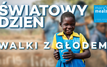 Dziewcznka trzymająca kubek z napisem Światowy Dzień Walki z Głodem