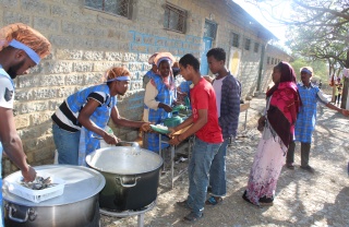 A queue of people receiving food aid from an Internally Displaced People's centre