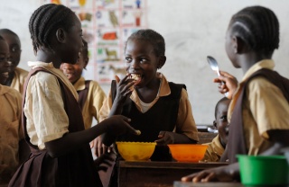 young children in group smiling at one another and eating food
