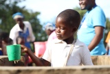 A close up of a child smiling at a mug