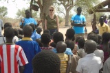 Two men and a woman speaking to a group of people assembled in front of them