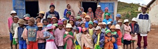 A group of children and adults stand in front of a building