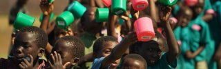 A group of children waving colourful mugs in the air