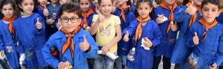 A group of children holding sandwiches and giving the camera thumbs up