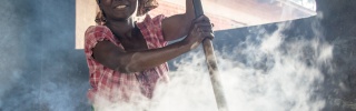 woman stirring a huge steaming cauldron smiling at camera