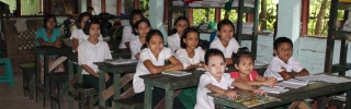 Pupils in school sitting at desks and looking at the camera