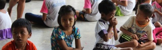 Children kneeling with bowls in front of them