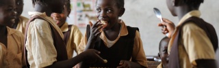 young children in group smiling at one another and eating food