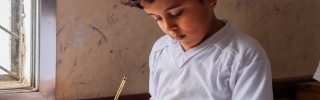 young boy sitting at a desk doing school work