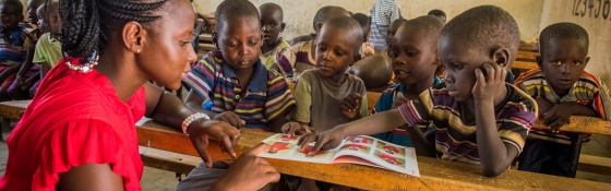 Teacher giving lesson to children listening attentively in class