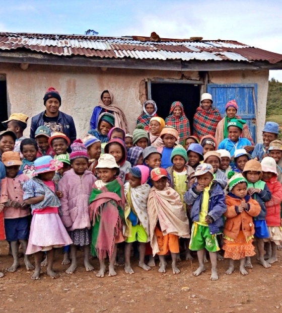A group of children and adults stand in front of a building