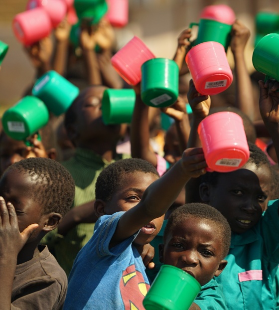 A group of children waving colourful mugs in the air
