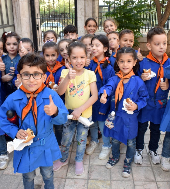 A group of children holding sandwiches and giving the camera thumbs up