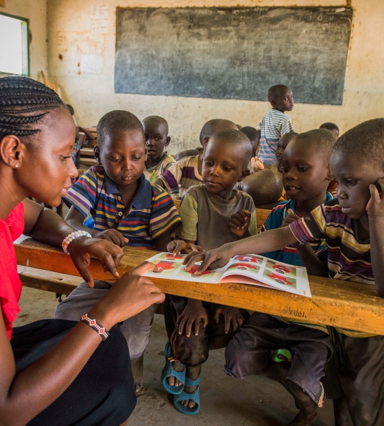 Teacher giving lesson to children listening attentively in class