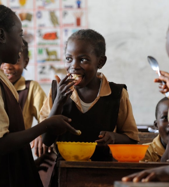 young children in group smiling at one another and eating food