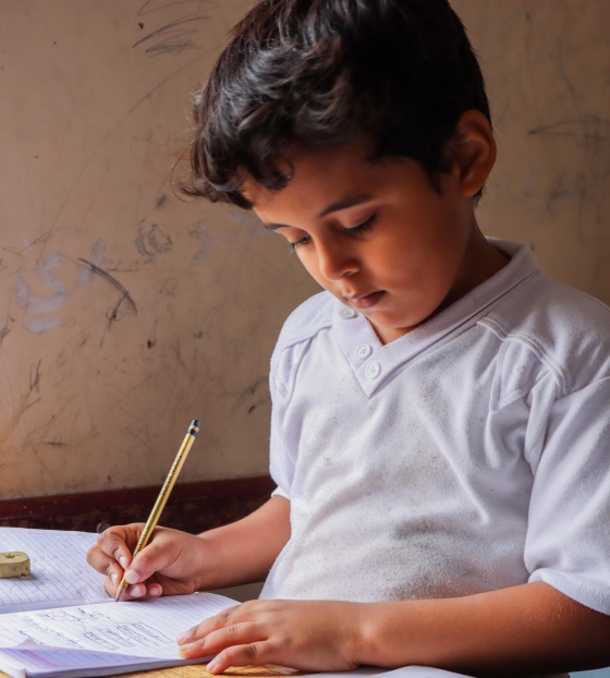 young boy sitting at a desk doing school work