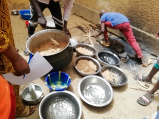 A collection of bowls sitting on a sandy floor, some containing rice