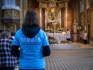Woman in a church with her back to camera staring at the altar