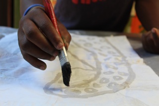 close up of a child's hand drawing an angel on white paper