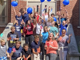 A group of people cheering in celebration and releasing balloons