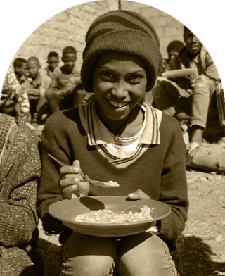 Dziecko w Etiopii siada, aby jeść w szkole.