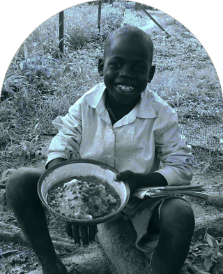 Dziecko w Południowym Sudanie siada, aby jeść w szkole.
