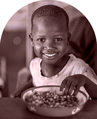 Dziecko w Kenii siada, aby jeść w szkole.